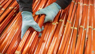 A worker lifts a bundle of copper windings.